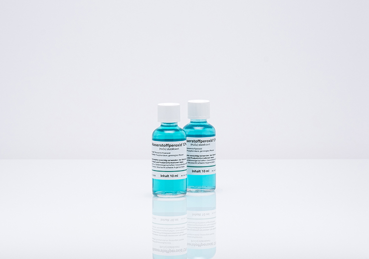 Warnetiketten für die chemische Industrie von robos-labels auf zwei Glasflaschen mit blauer Flüssigkeit