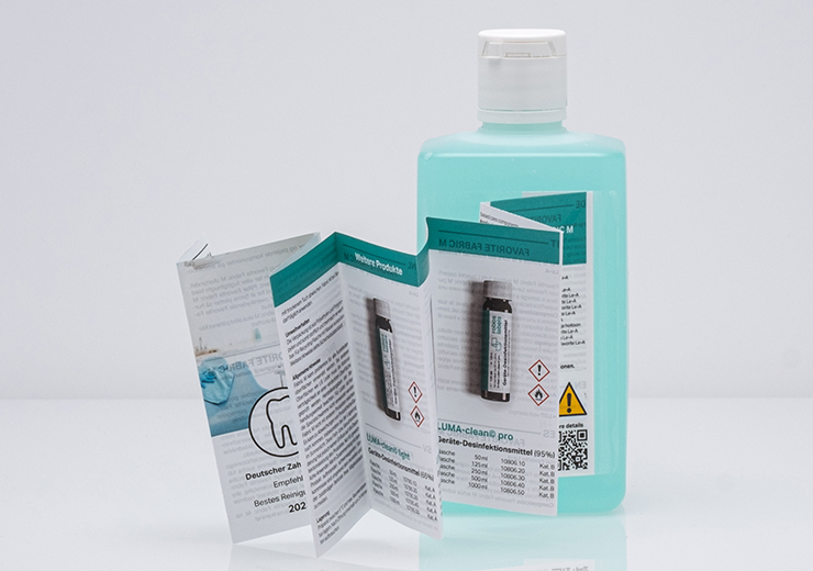 Bookletetikett mit Produktinformationen auf Kunststoffflasche, unverlierbar am Produkt.